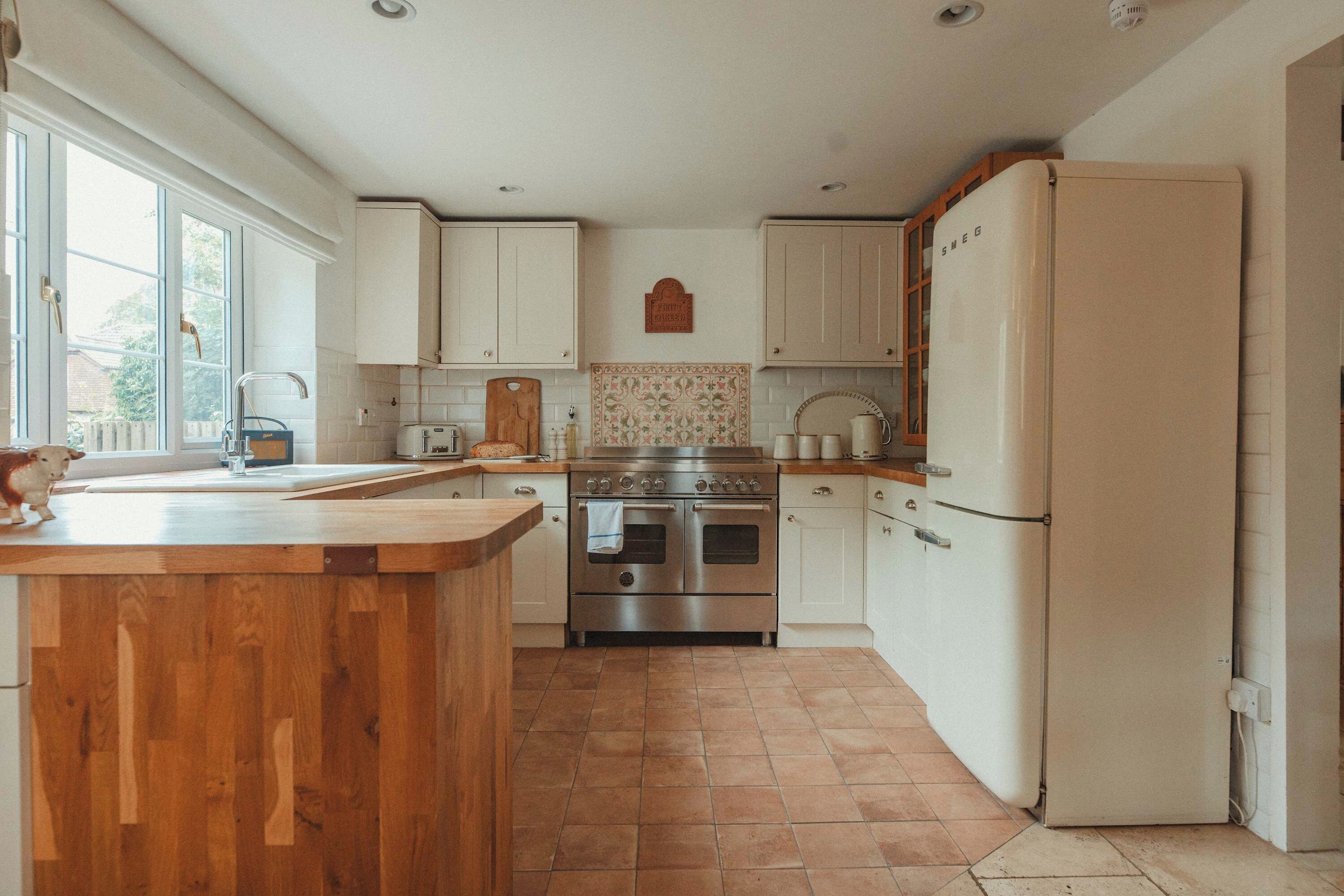 A kitchen with a wooden island, stainless steel appliances, and a white refrigerator.