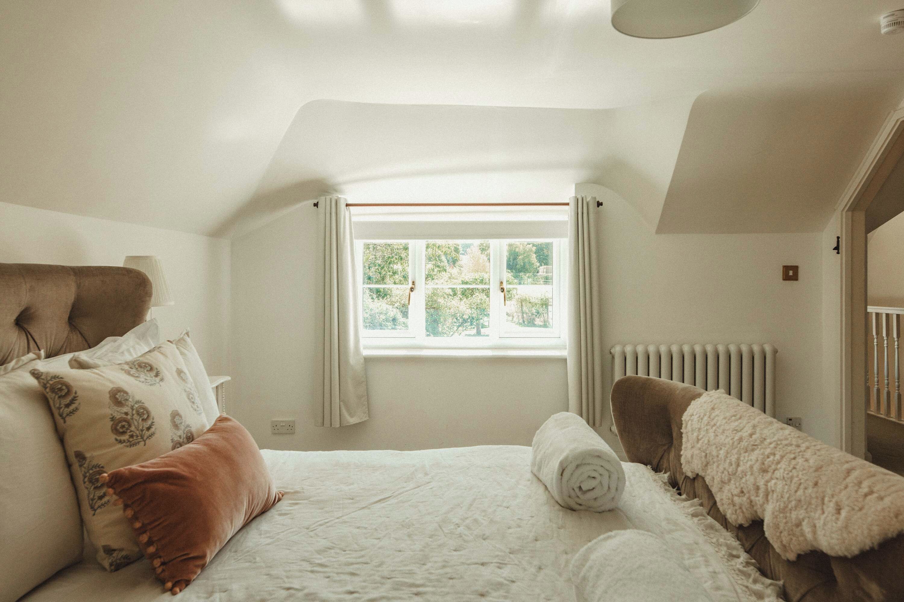 Ein Schlafzimmer mit einem Bett, einem Fenster, einer Heizung und einer Tür.