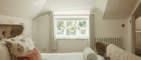 Ein Schlafzimmer mit einem Bett, einem Fenster, einer Heizung und einer Tür.