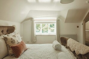 Un dormitorio con cama, ventana, radiador y puerta.