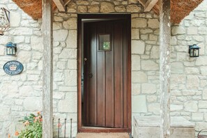 Un edificio de piedra con una puerta de madera, un cartel que dice 'KINGS COTTAGE' y dos faroles en la pared.