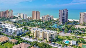 A high-rise hotel with multiple floors, a swimming pool, and a beach view. - Oceangoing Condo With Pool and Steps to Beach and Food (Marco Island)