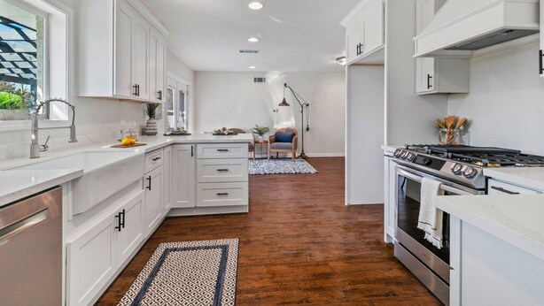 Una cocina moderna con armarios blancos, una isla central y una estufa.