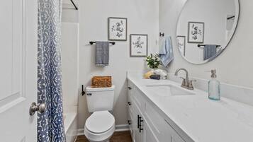 A bathroom with a toilet, sink, mirror, and framed floral artwork on the wall.