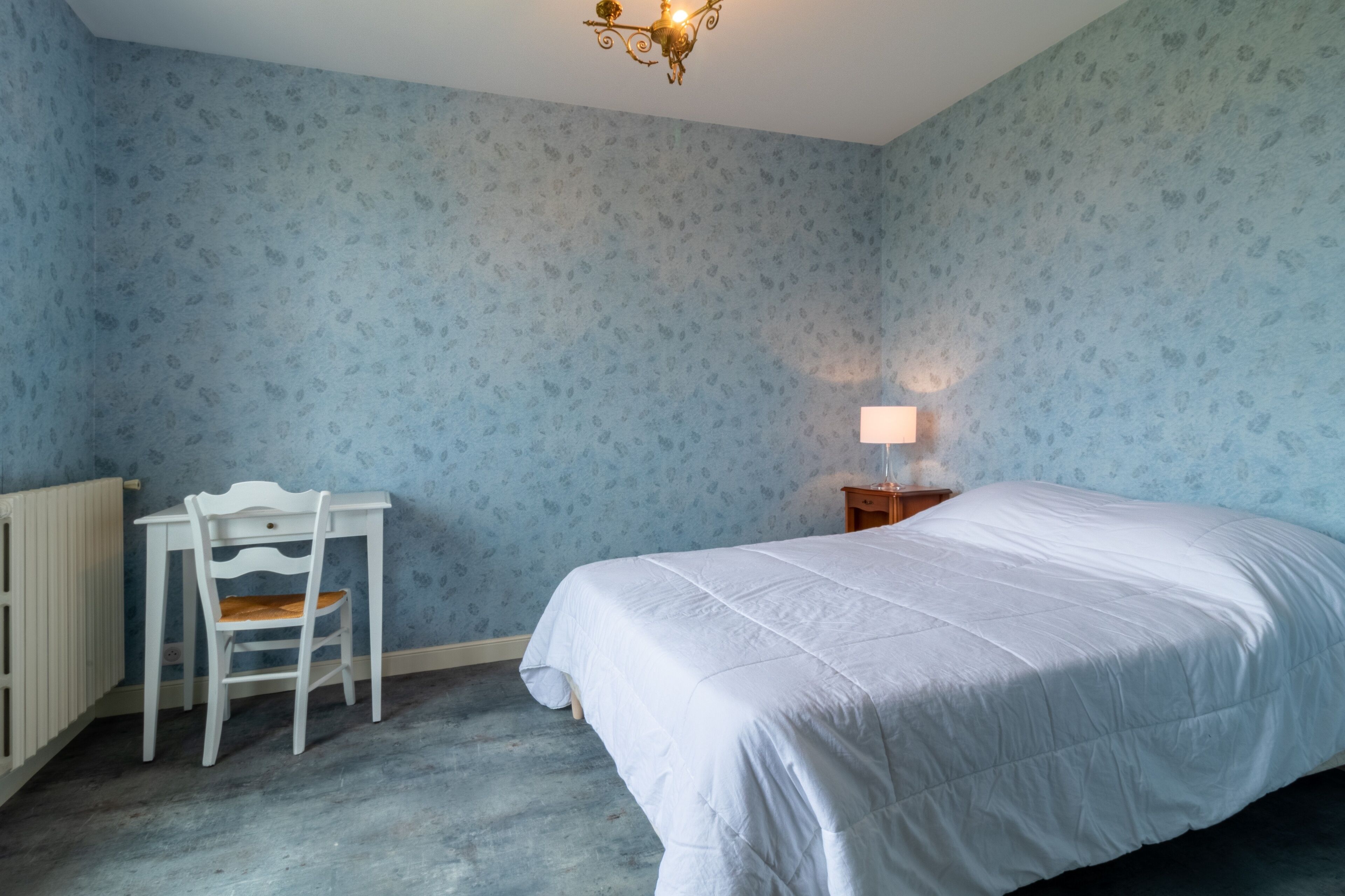 A bedroom with a bed, a desk, and a chair.
