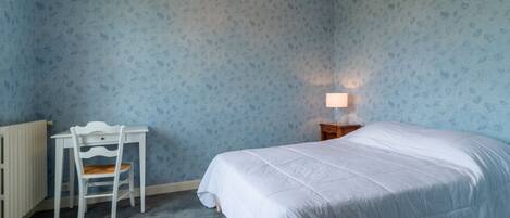 A bedroom with a bed, a desk, and a chair.