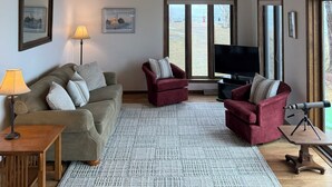 A living room with a ceiling fan, a sofa, two armchairs, a TV, and a large window. - Waterfront Island-View Retreat on Rileys Point - Private Door County Escape (Sturgeon Bay)