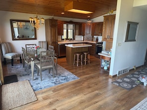 A spacious kitchen with wooden cabinets, a central island, and a dining area with a table and chairs.