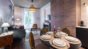 A modern living room with a dining area, featuring a fireplace, a sofa, and a dining table set for four.