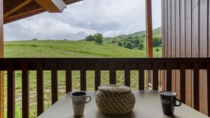 A wooden deck with a table, two mugs, and a woven basket.