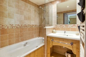 Ein Badezimmer mit einer Badewanne, einem Holzkosmetikschrank mit Waschbecken und einem Spiegel.