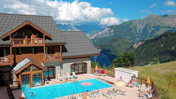 A hotel with a pool, outdoor seating, and mountain views.