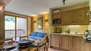 A cozy cabin-style room with a dining area, a kitchenette, and a large window overlooking a deck.