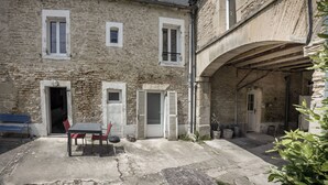 Ein Steinhaus mit Innenhof, einem Tisch mit Stühlen und einer Bank.