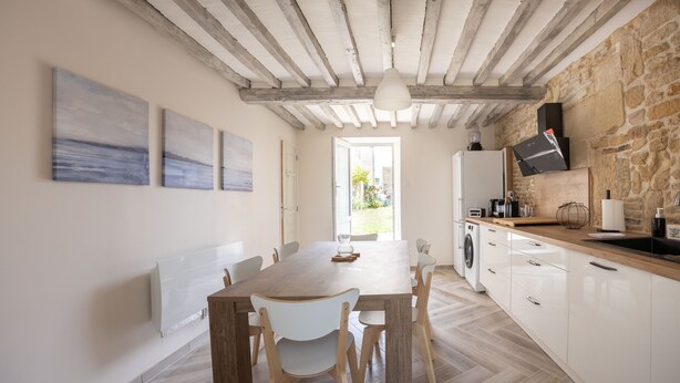 Eine moderne Küche mit Holztisch und -stühlen, weißen Schränken und einer Steinwand.