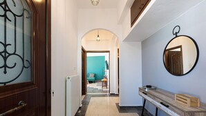 A hallway with a wooden door, a radiator, a bench, and a mirror on the wall. - Beautiful 2-bed Apartment in Rethymno (Rethymno)