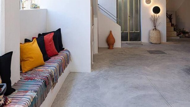 A spacious interior with a modern staircase, a seating area with colorful cushions, and a unique ceiling design with exposed ropes and lighting. - Beautiful 2-bed Apartment in Rethymno (Rethymno)