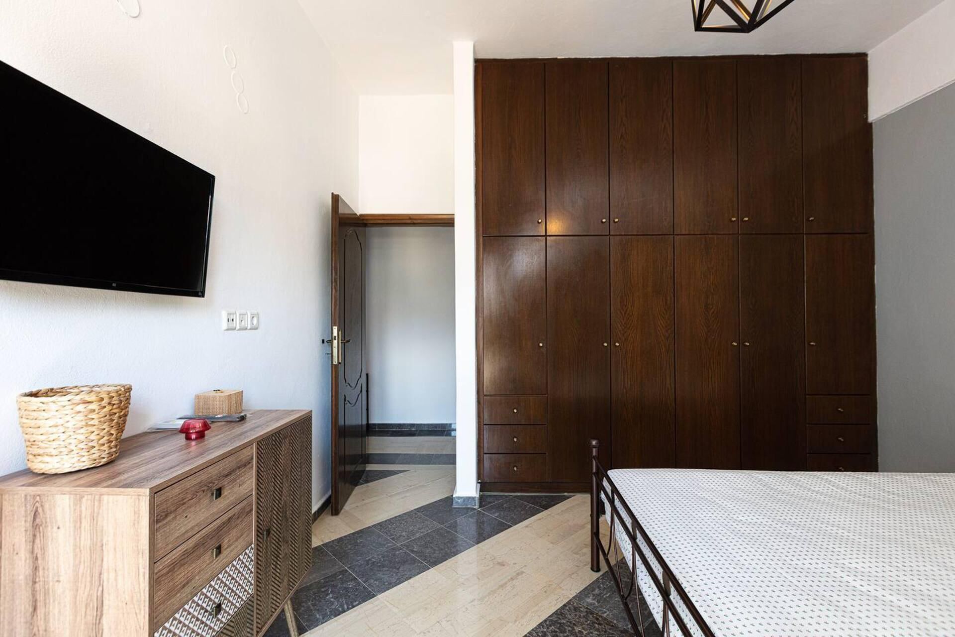 A bedroom with a bed, wooden dresser, and a wardrobe.