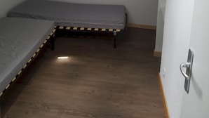 Ein kleiner, schummrig beleuchteter Raum mit zwei Etagenbetten, einer schrägen Decke und einer einzelnen Lampe.