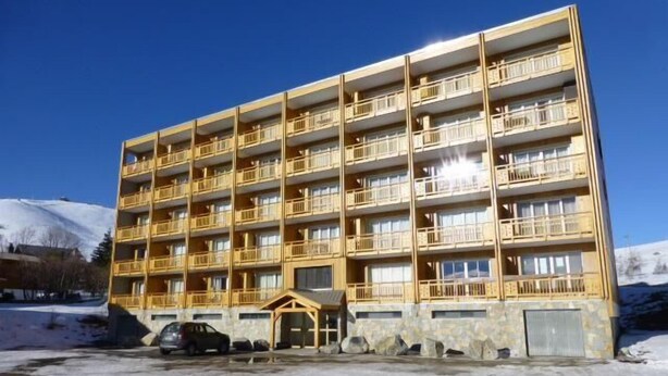 Un hôtel à plusieurs étages doté de balcons, d’une entrée couverte et d’un espace de stationnement.