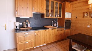 Une cuisine avec des meubles de rangement en bois, un plan de travail noir, un évier et une cuisinière.