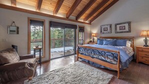 Une chambre avec un plafond en bois, un grand lit, un canapé et une vue sur l’extérieur.