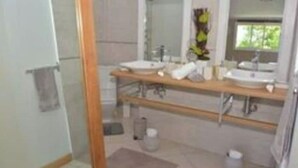 Un baño moderno con dos lavamanos, un espejo y zona de ducha.