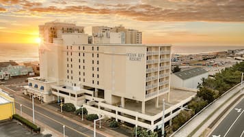 Un immeuble à plusieurs étages portant l’enseigne « Ocean Key Resort », un parking et une vue sur la plage au coucher du soleil.