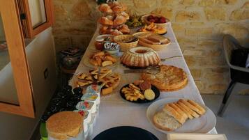 Un tavolo da buffet con diversi cibi e condimenti, sullo sfondo di un muro in pietra.