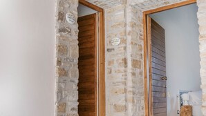 Una entrada de paredes de piedra con puertas de madera y un pequeño escalón que da a un suelo de baldosas.