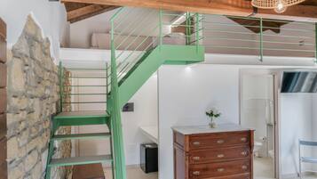 Un interno moderno con una scala in metallo verde, un comò in legno e un muro in pietra.