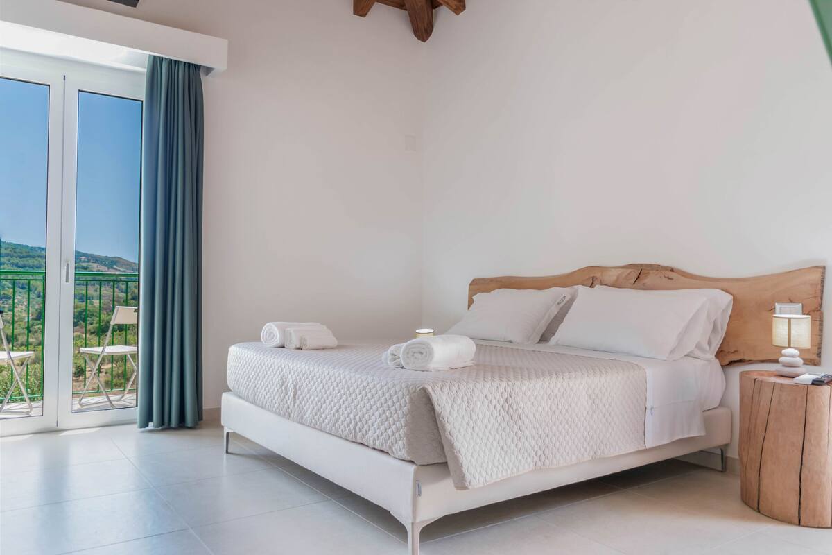 Une chambre avec un lit, une table de chevet, une vue sur l’extérieur et un balcon.