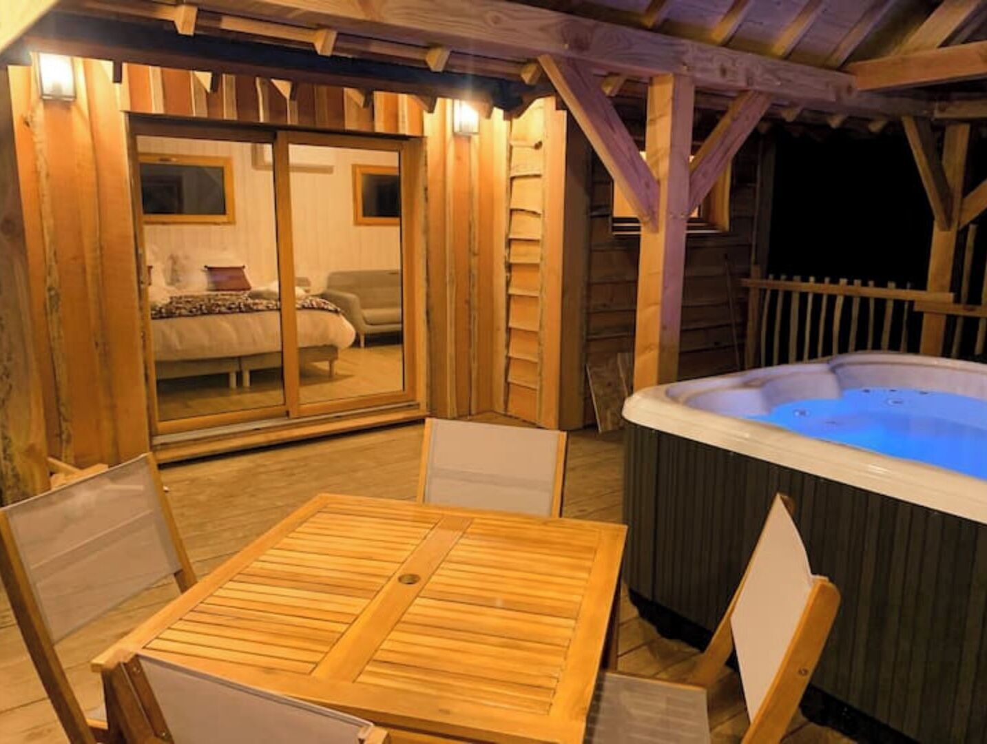 A wooden deck with a hot tub, a table, and chairs.