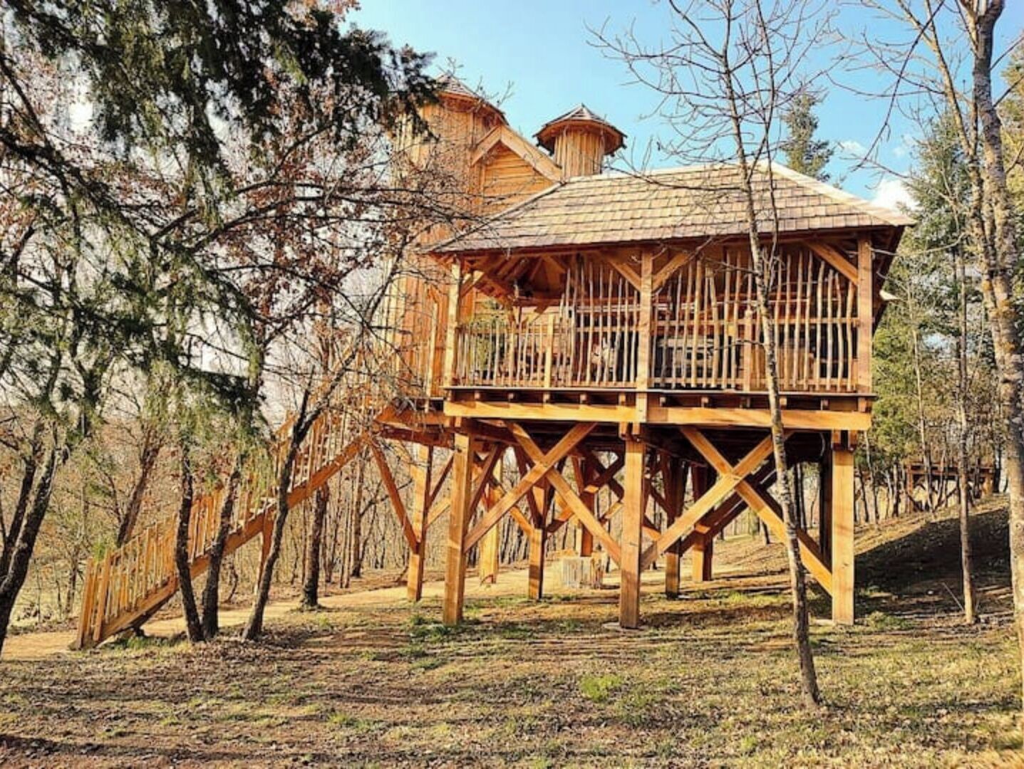 Une cabane en bois dotée d’un balcon, entourée d’arbres.