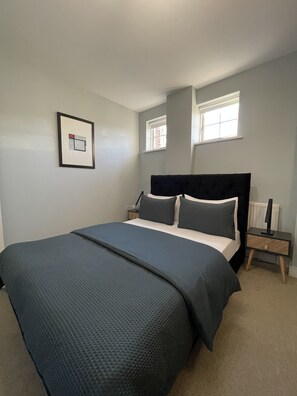 Relax in this serene bedroom with a large bed, bedside table, and framed picture.