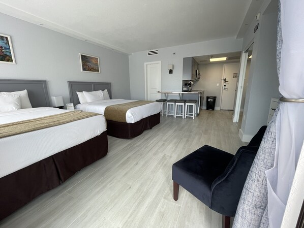 Habitación de hotel con dos camas, un pequeño kitchenette, comedor y zona de estar separada.