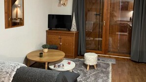 Un salon chaleureux avec un meuble en bois, une télévision, une table ronde et un canapé.