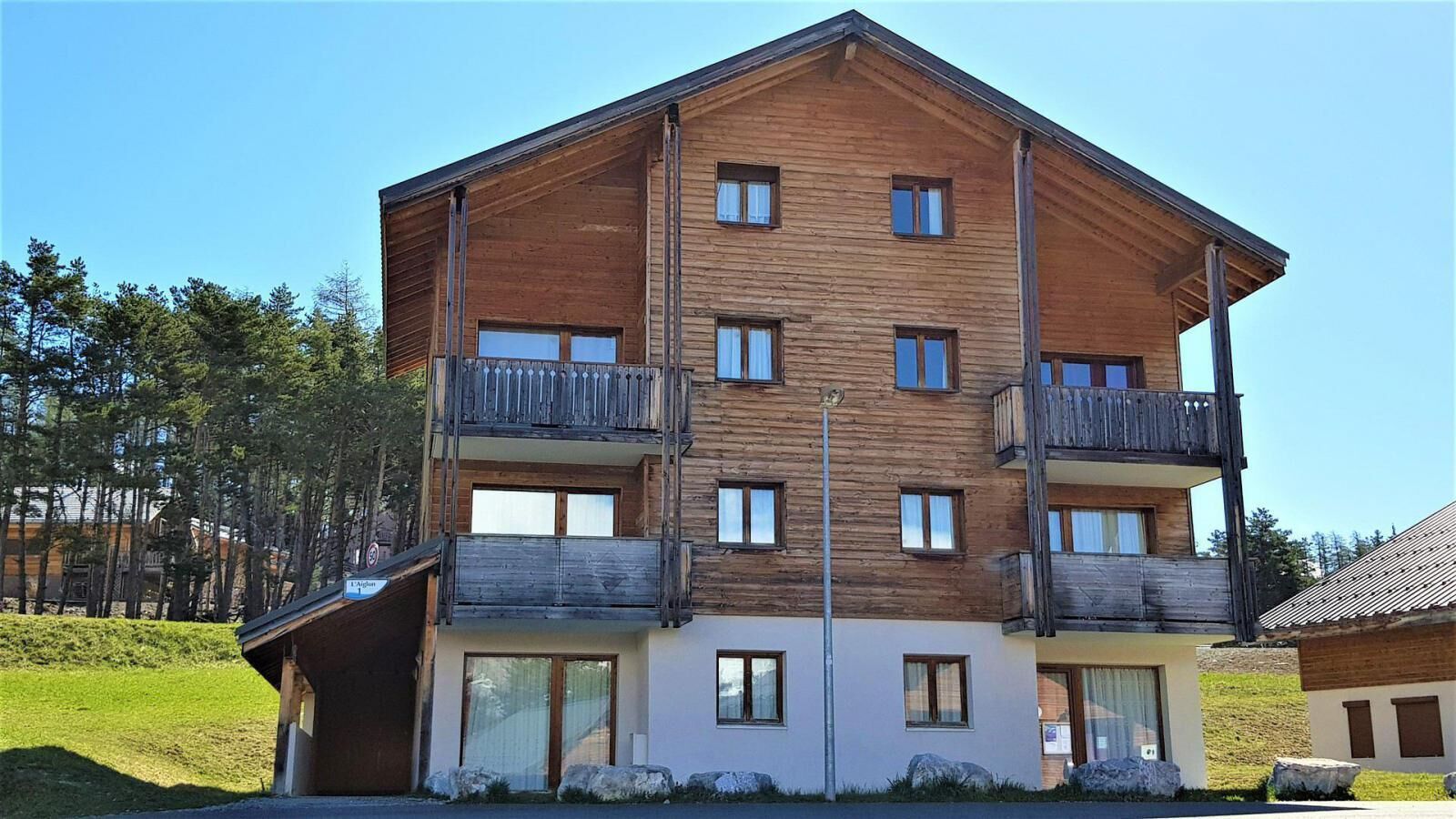 Un immeuble en bois à plusieurs étages, doté de balcons, de grandes fenêtres et d’un toit plat.