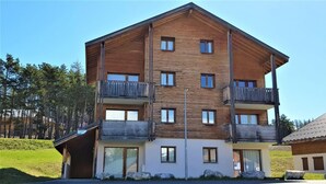Un immeuble en bois à plusieurs étages, doté de balcons, de grandes fenêtres et d’un toit plat.