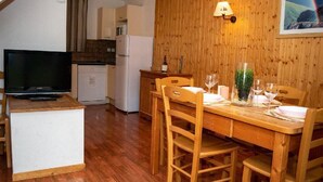 Uma cozinha compacta com micro-ondas, geladeira e uma televisão sobre um suporte.