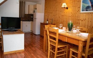 Una cucina compatta con forno a microonde, frigorifero e televisore su un mobile.