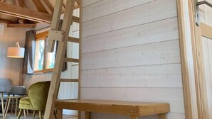 A wooden interior with a loft bed, a ladder, and a shelf unit. - Cabane Château Luxe Jacuzzi/spa Privé - 2 à 6 Pers (Vieille-Brioude)