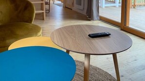 A wooden interior with a round table, a yellow sofa, and a large window. - Cabane Château Luxe Jacuzzi/spa Privé - 2 à 6 Pers (Vieille-Brioude)