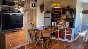 Een ruime keuken met houten kasten, een eethoek met een houten tafel en stoelen, en een ingebouwde televisie.
