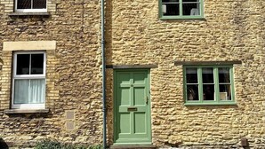 Un bâtiment en pierre avec une porte verte et de nombreuses fenêtres.