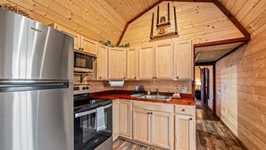 Eine Küche mit Holzausstattung, einem Edelstahlkühlschrank, einer Mikrowelle und einem Herd.