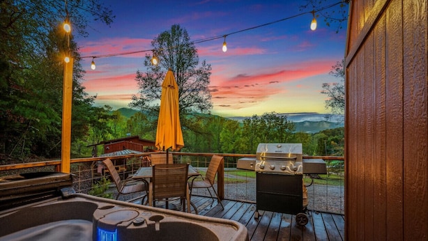 Eine Holzterrasse mit Whirlpool, Grill und Stühlen unter Lichterketten.
