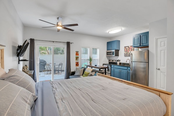 A compact studio apartment with a bed, kitchenette, and a ceiling fan. - Tropical Retreat! 2 minutes to Beach and Pool/Jacuzzi! (Panama City Beach)
