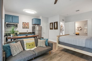 A compact living space with a kitchenette, a sofa, a bed, and a dining area. - Tropical Retreat! 2 minutes to Beach and Pool/Jacuzzi! (Panama City Beach)