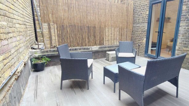 Eine Terrasse mit Korbmöbeln, einem kleinen Tisch und einem Blumentopf.